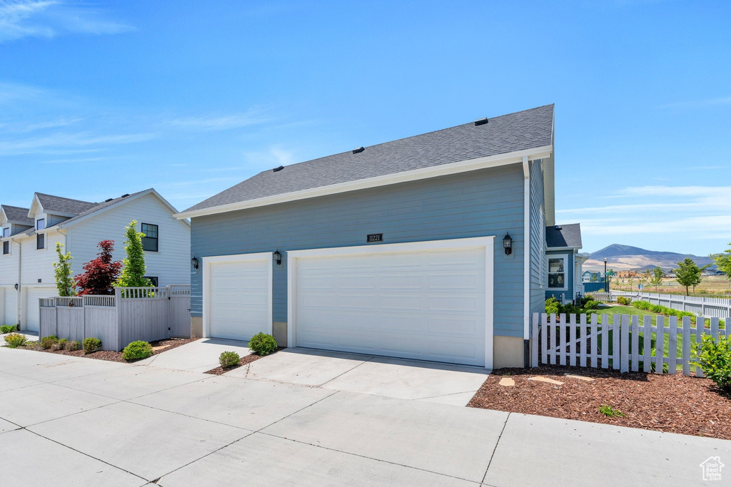 View of side of property featuring concrete driveway, a garage, and a mountain view