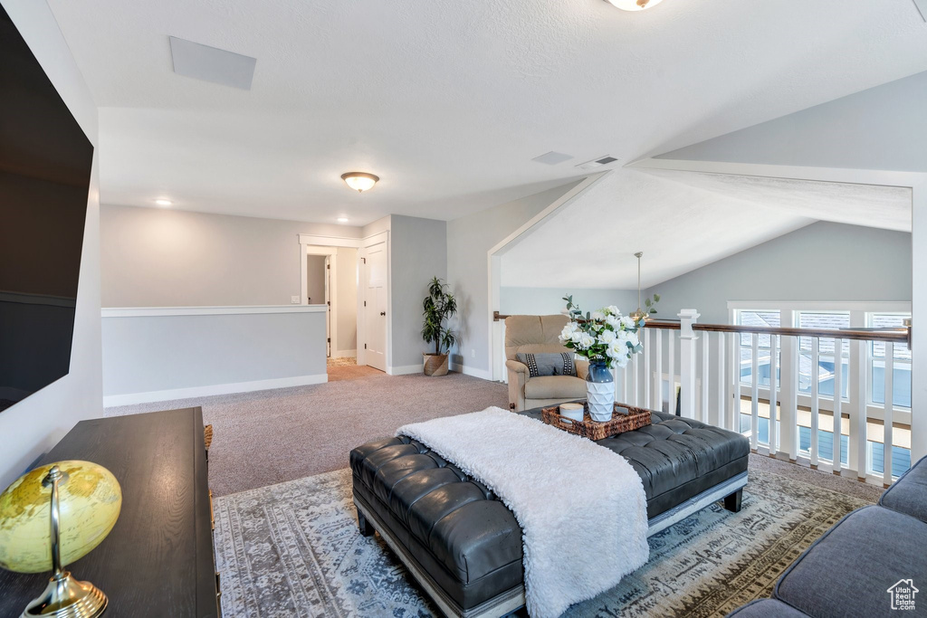 Living room with carpet flooring, vaulted ceiling, and baseboards