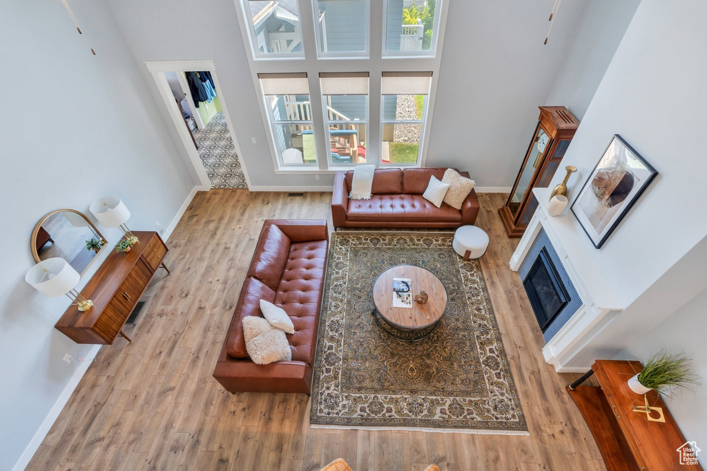 Living room featuring wood finished floors, baseboards, a towering ceiling, and a glass covered fireplace