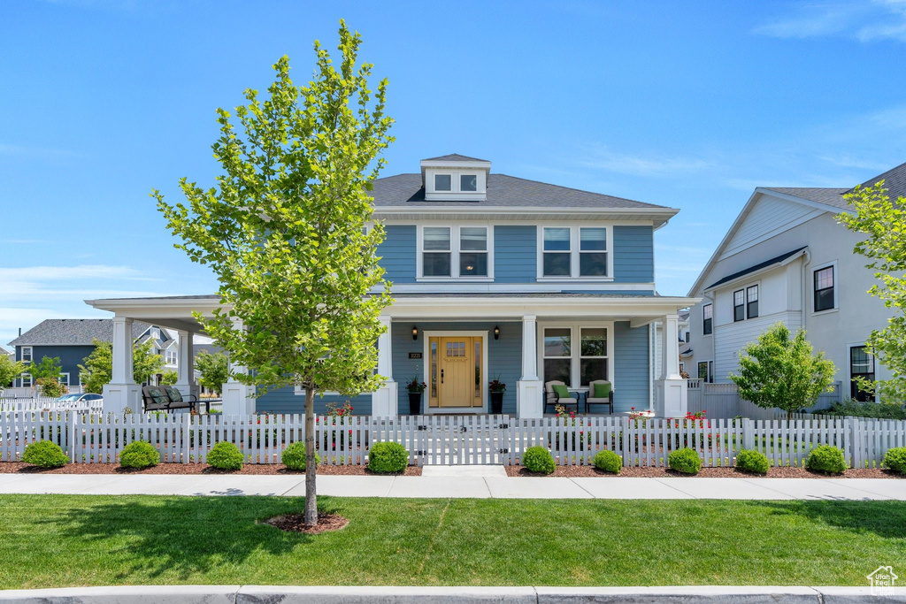 Traditional style home with covered porch and a front yard