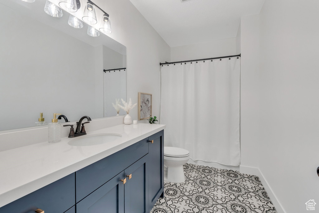 Full bath with vanity, toilet, and baseboards