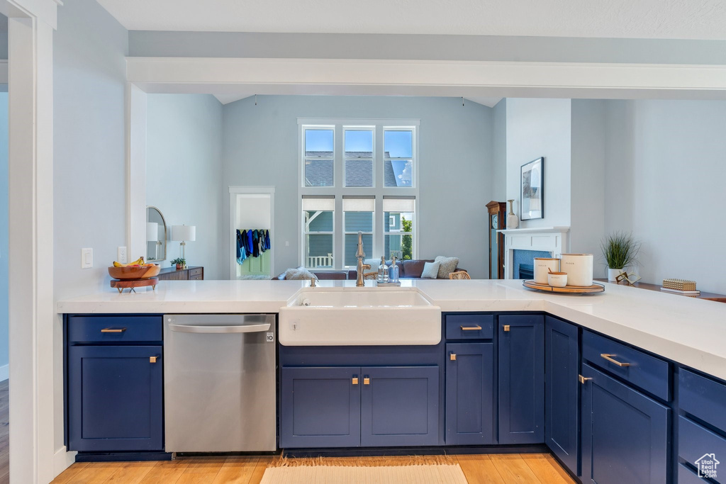 Kitchen featuring dishwasher, a sink, light wood-type flooring, light countertops, and blue cabinetry