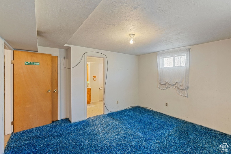 Unfurnished bedroom with light carpet, a textured ceiling, and connected bathroom