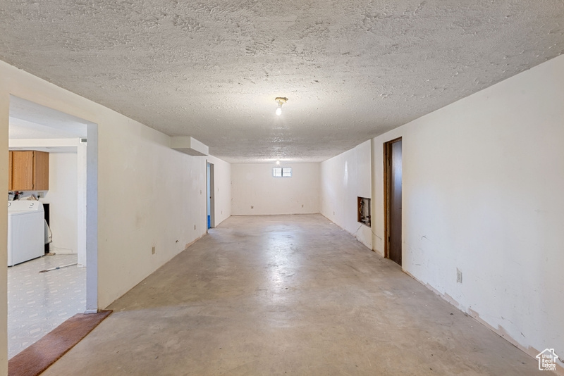Empty room featuring washer / clothes dryer, finished concrete floors, and a textured ceiling