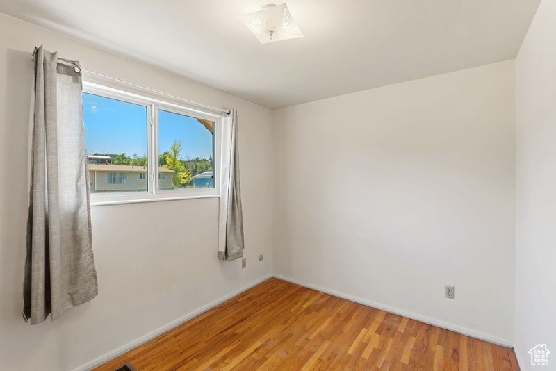 Unfurnished room with wood finished floors, a skylight, and baseboards