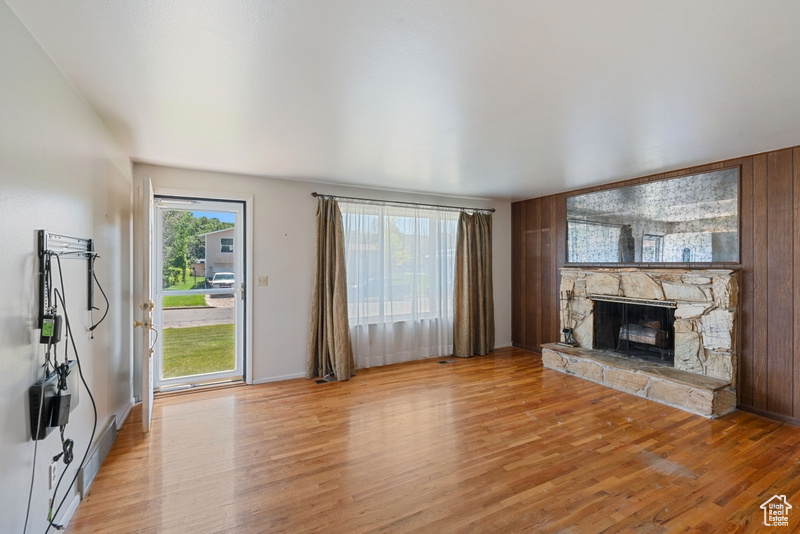 Unfurnished living room with light wood-style floors and a stone fireplace