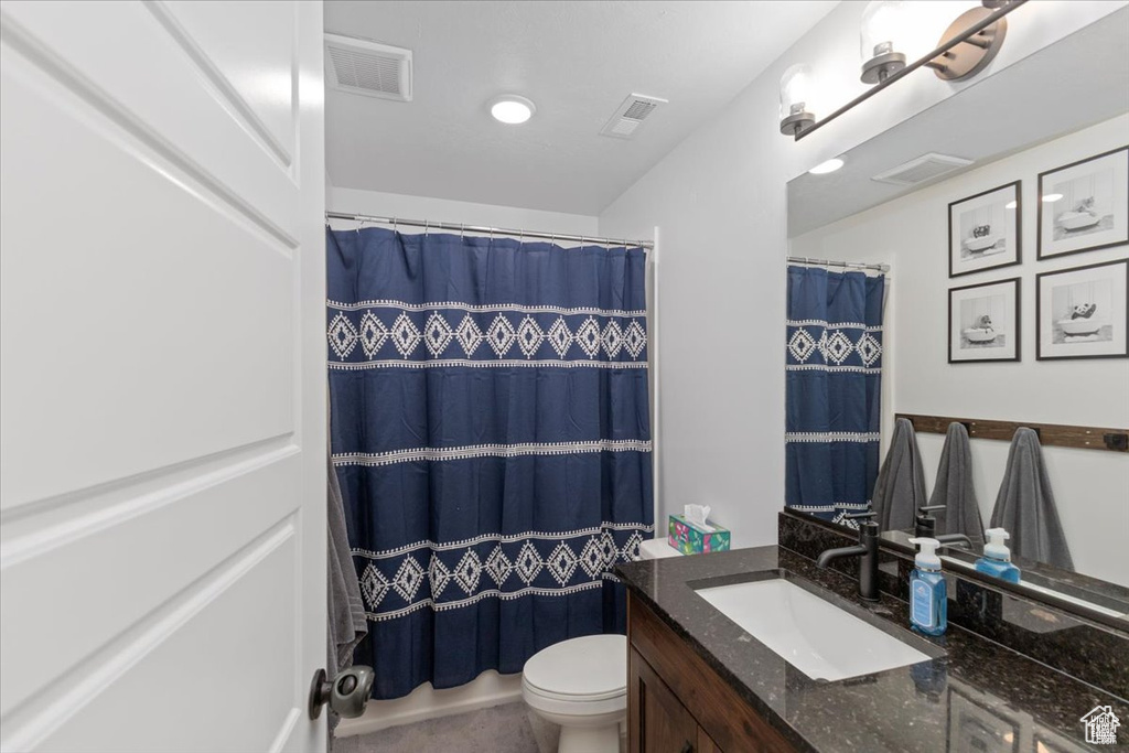 Bathroom with vanity, toilet, and curtained shower