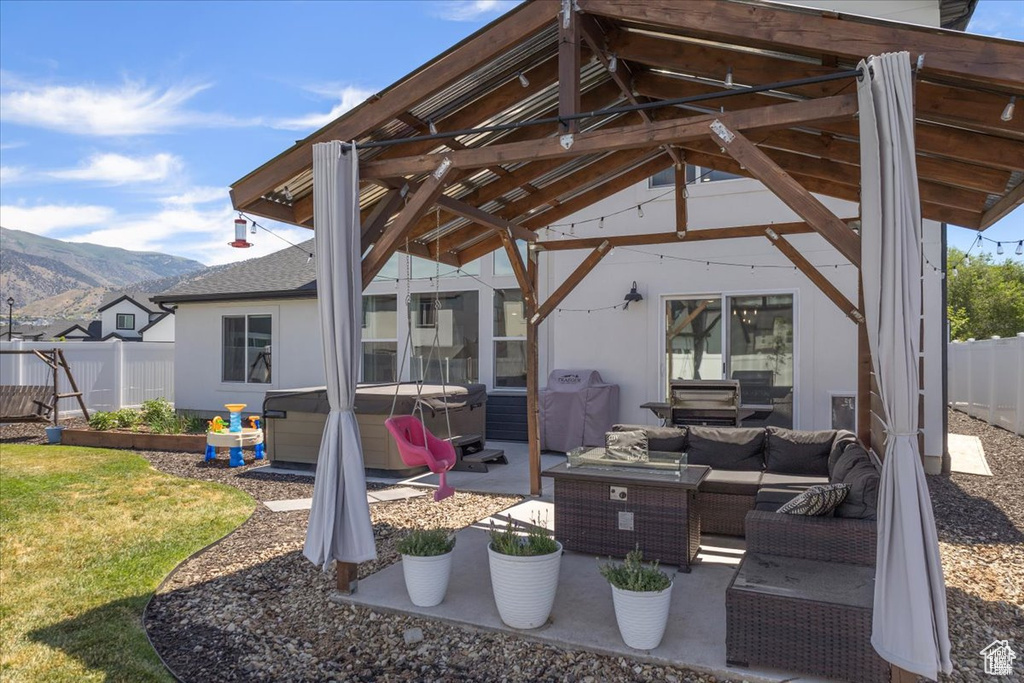 View of patio with a hot tub, outdoor lounge area, a mountain view, area for grilling, and a gazebo