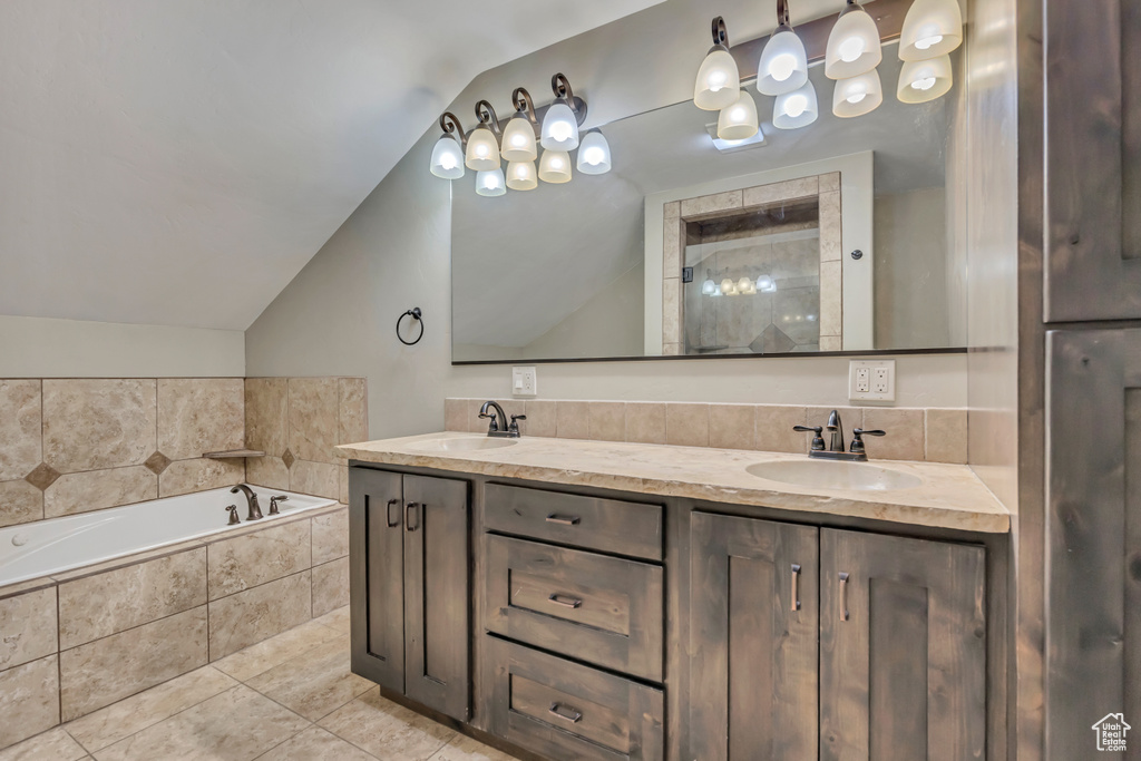 Bathroom featuring vaulted ceiling, double vanity, a garden tub, and tile patterned floors