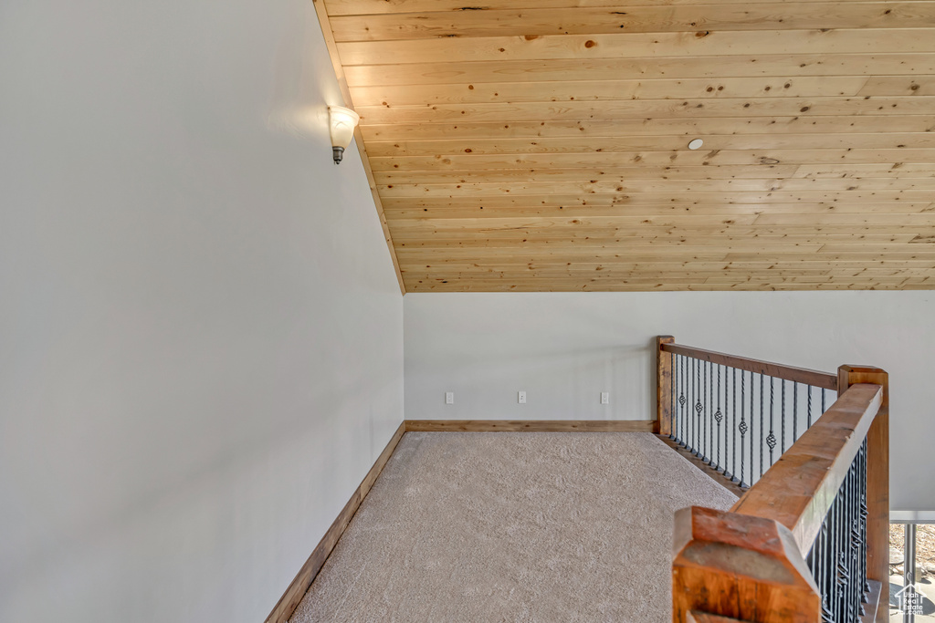 Hallway with wooden ceiling, carpet floors, baseboards, lofted ceiling, and an upstairs landing