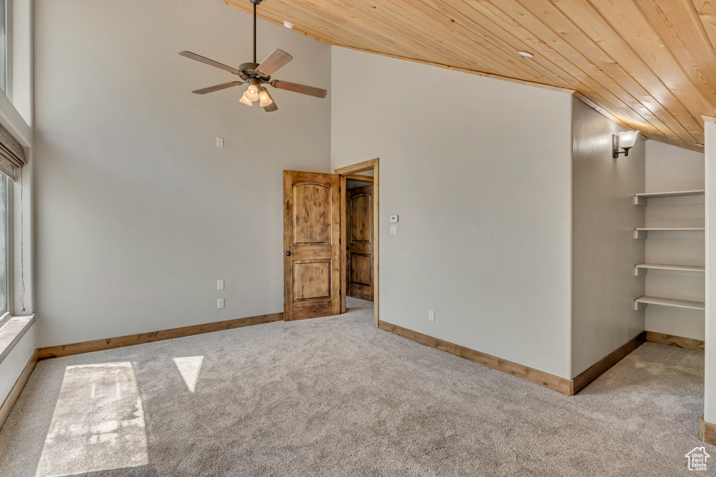 Carpeted spare room with wood ceiling, a ceiling fan, baseboards, and high vaulted ceiling