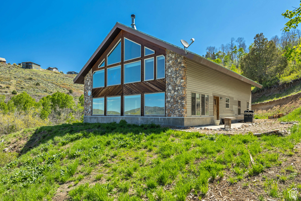 Back of house with stone siding and a patio