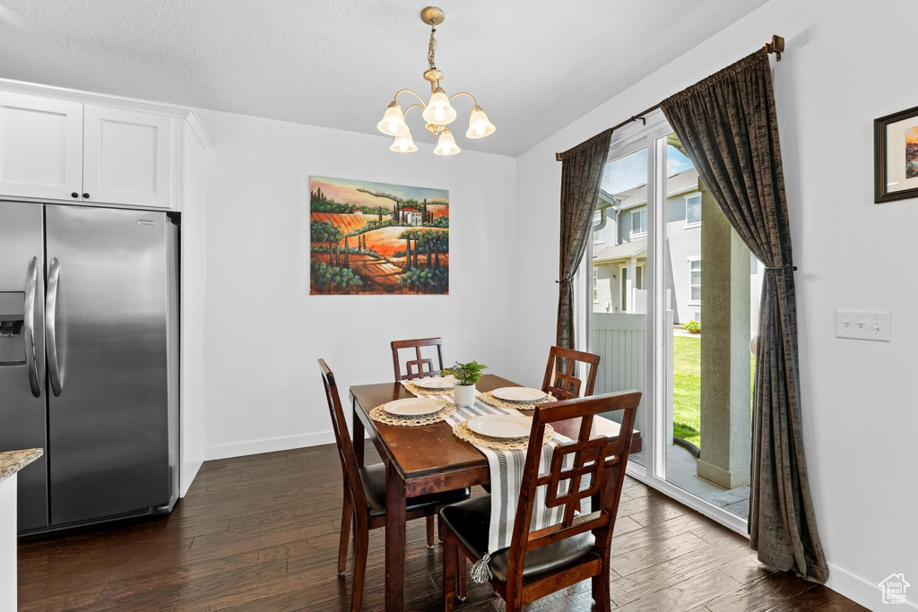 Dining area with dark wood-type flooring, a chandelier, and baseboards
