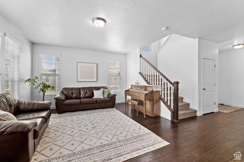 Living area featuring stairway, hardwood / wood-style flooring, a textured ceiling, and baseboards