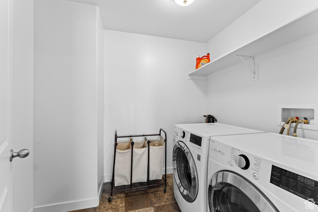 Laundry area with separate washer and dryer, dark stone finish floors, and baseboards