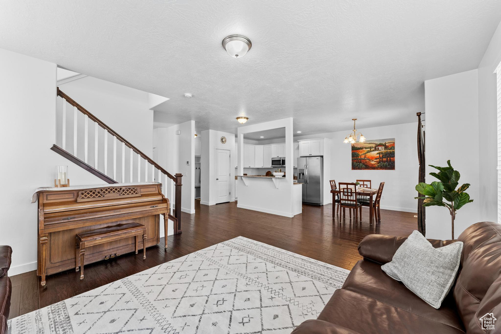 Living room featuring stairway, a chandelier, baseboards, and dark wood finished floors