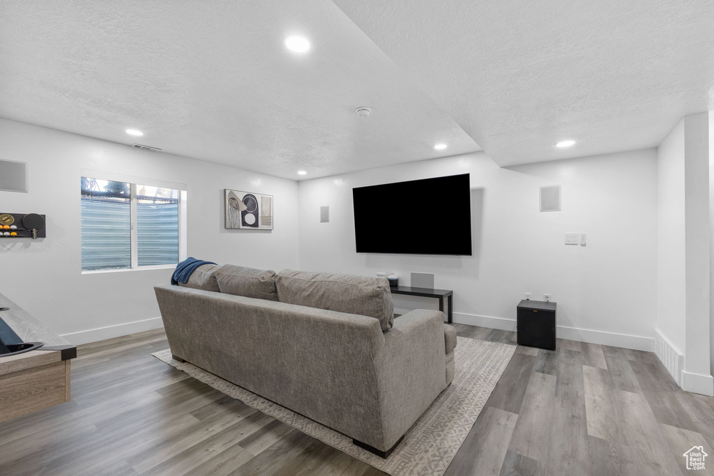 Living area featuring a textured ceiling, recessed lighting, baseboards, and wood finished floors