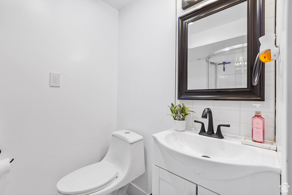 Bathroom featuring toilet, vanity, tasteful backsplash, and an enclosed shower