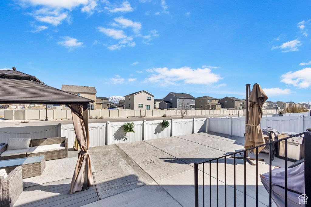 Fenced backyard with a residential view, a jacuzzi, a patio, and a gazebo