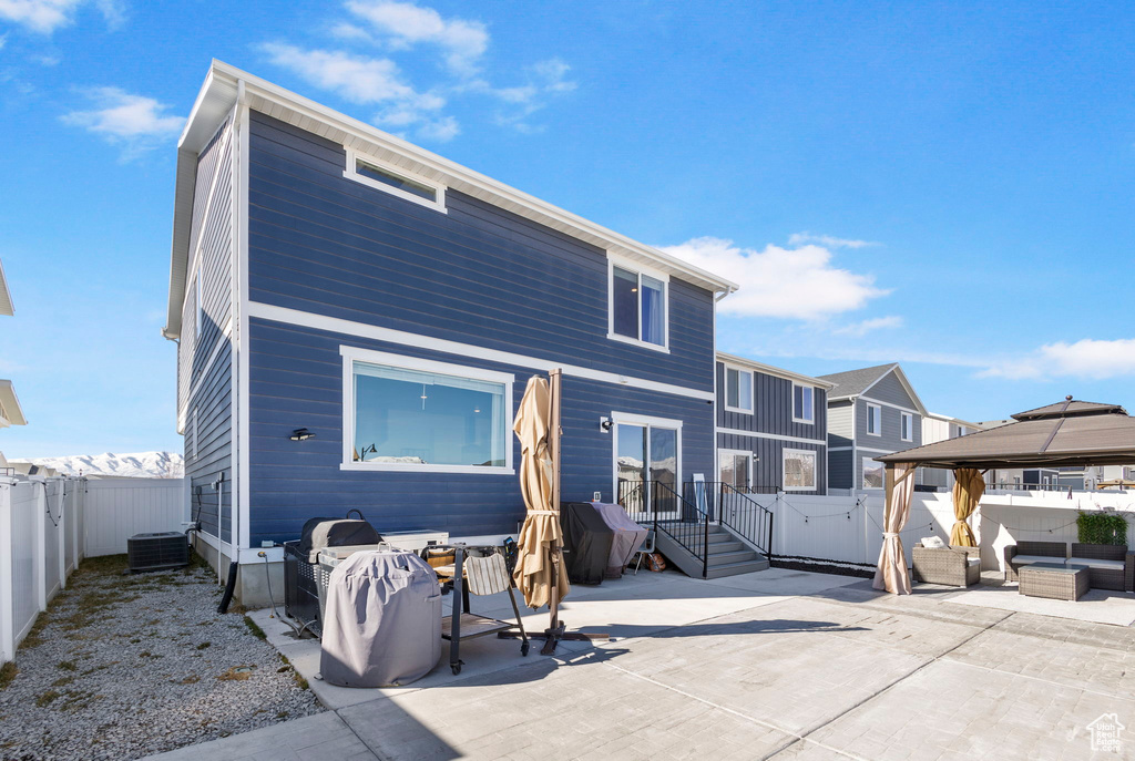 Rear view of property featuring a patio area, an outdoor hangout area, a fenced backyard, and a gazebo