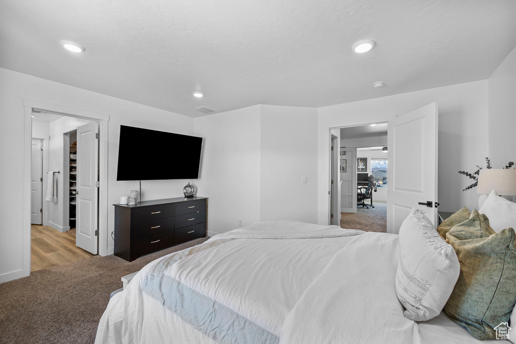 Bedroom featuring light carpet, recessed lighting, a spacious closet, and baseboards