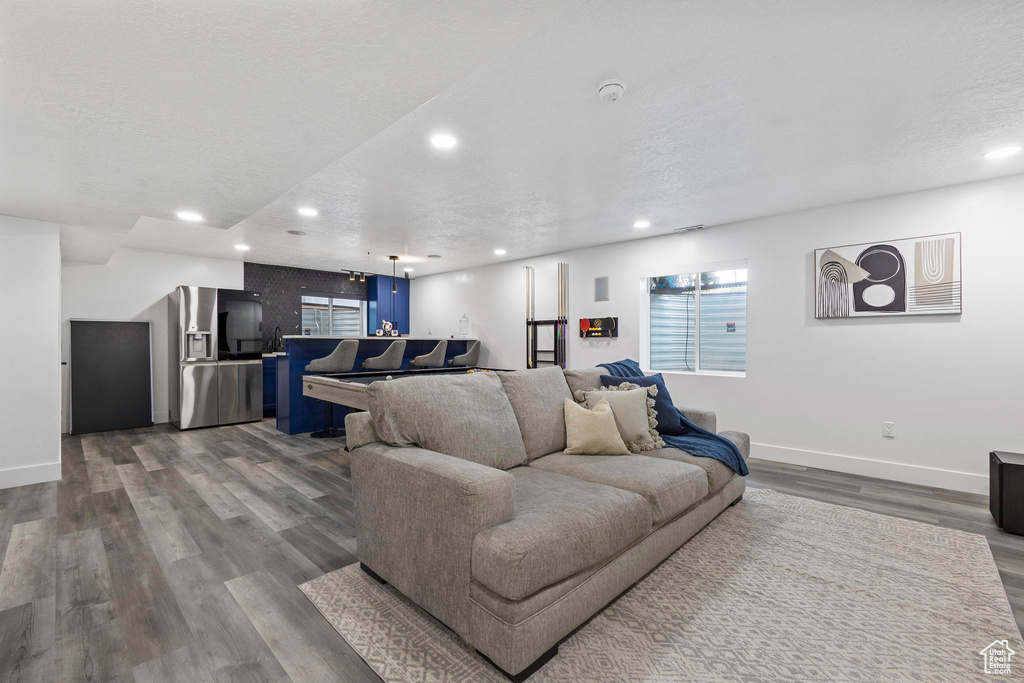 Living room featuring baseboards, wood finished floors, recessed lighting, and a textured ceiling