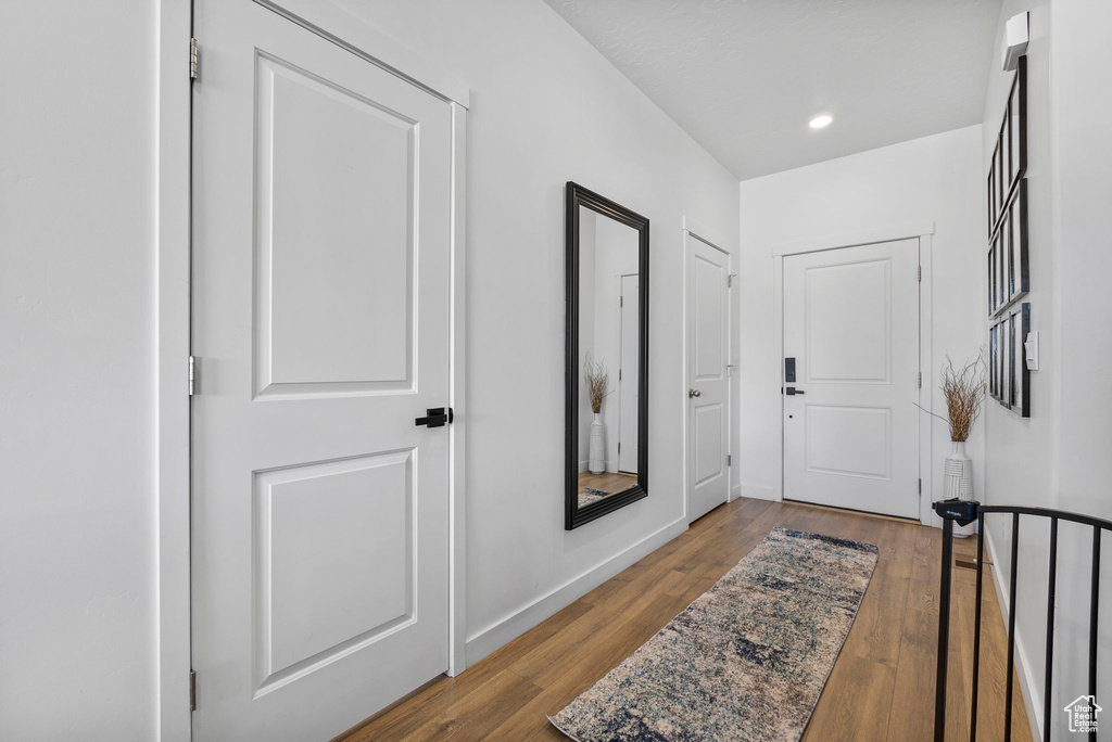 Doorway with wood finished floors, baseboards, and recessed lighting