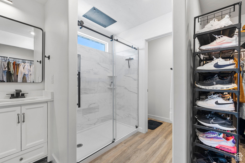 Bathroom featuring a stall shower, vanity, wood finished floors, and a walk in closet