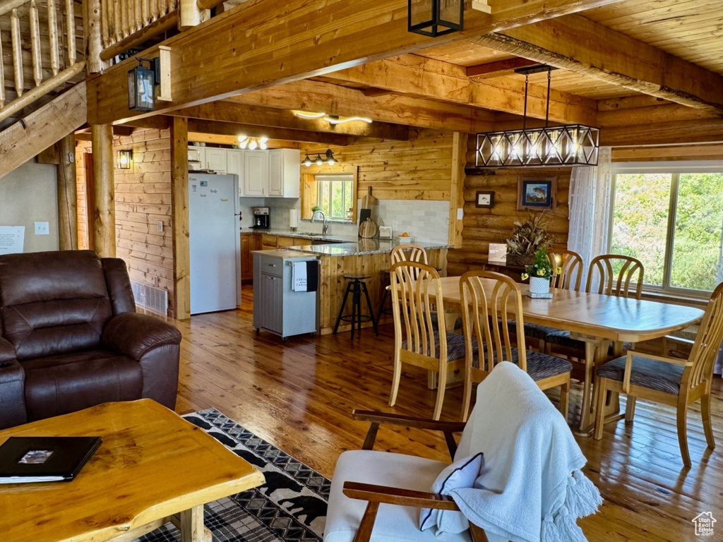 Dining area with wood-type flooring, a chandelier, and wooden ceiling with exposed beams