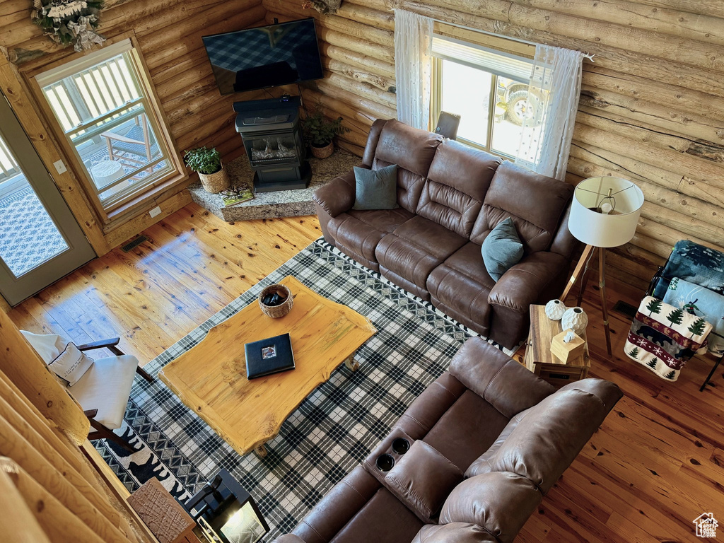 Living area with a wood stove, rustic walls, and hardwood / wood-style flooring
