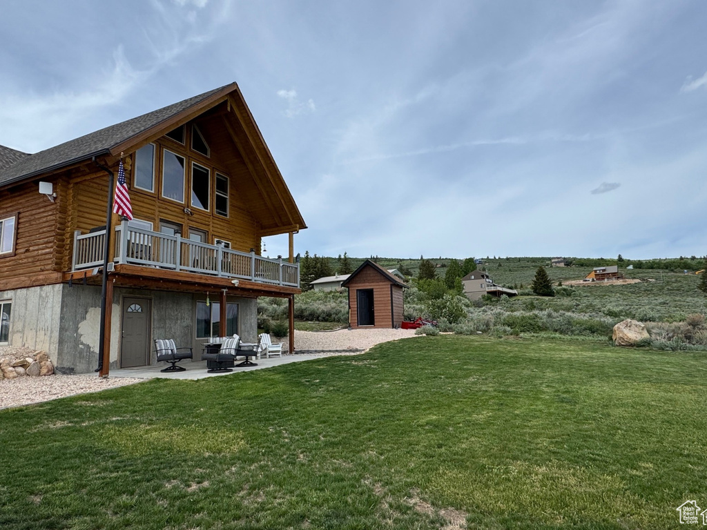 View of grassy yard featuring a patio and a wooden deck