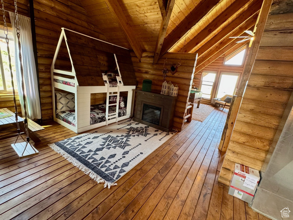 Living area featuring rustic walls, hardwood / wood-style floors, wooden ceiling, and a glass covered fireplace