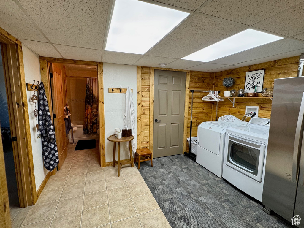 Washroom with washing machine and clothes dryer, wood walls, and tile patterned flooring