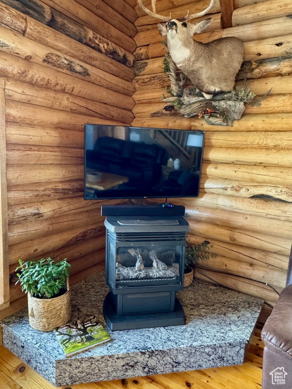 Detailed view of a wood stove, wood finished floors, and log walls