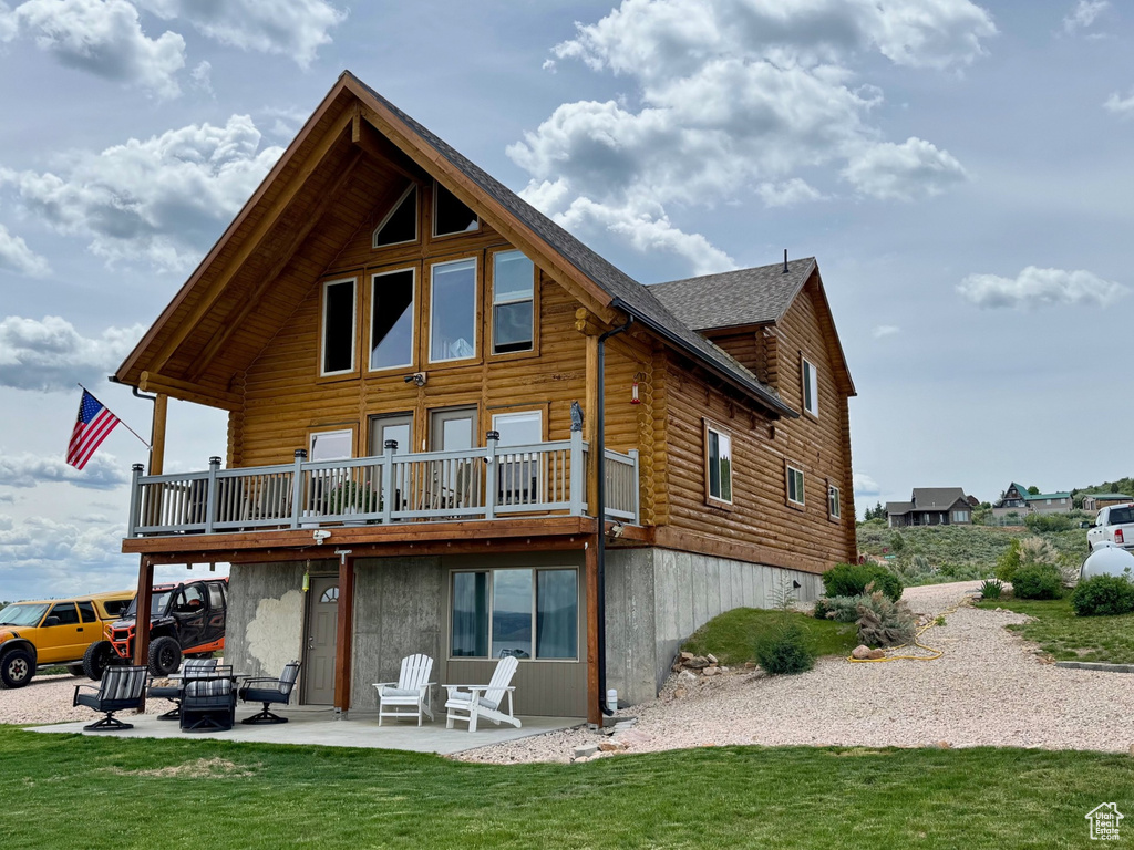 Back of property with log siding, a patio area, a yard, and a deck