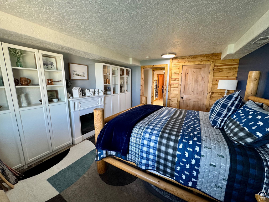 Bedroom with a textured ceiling, carpet floors, and wood walls
