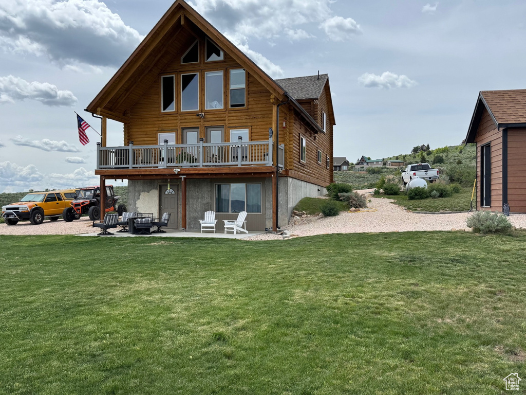 Rear view of property featuring a lawn, a patio area, and a wooden deck