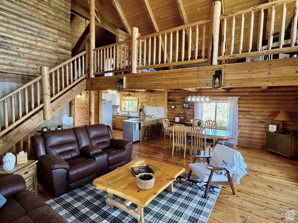 Living area featuring high vaulted ceiling, stairway, light wood-style floors, and wood ceiling with exposed beams