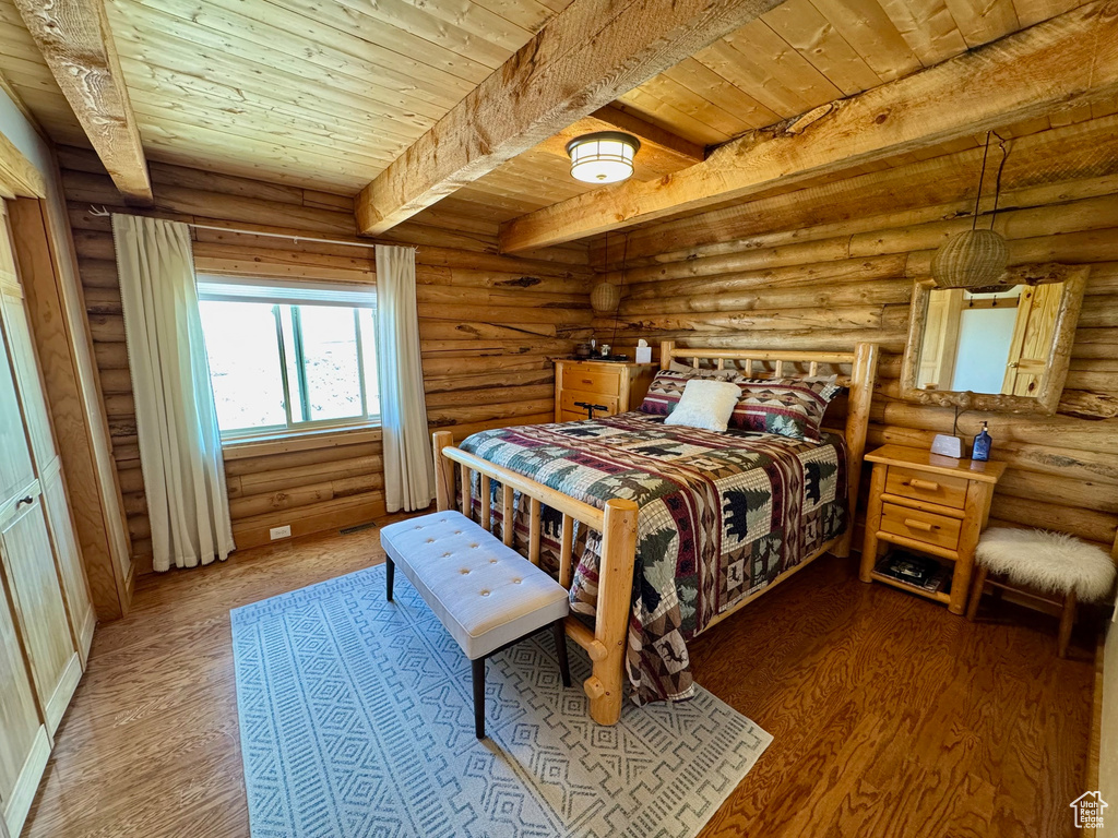 Bedroom featuring wooden ceiling with exposed beams, wood finished floors, and rustic walls