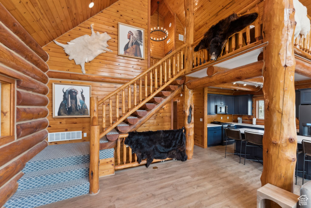 Stairway featuring high vaulted ceiling, wood ceiling, log walls, and wood finished floors