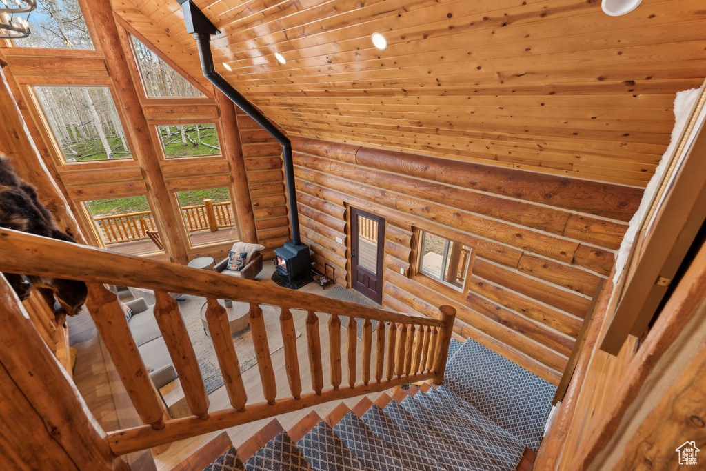 Stairs featuring log walls, a wood stove, wood ceiling, and healthy amount of natural light