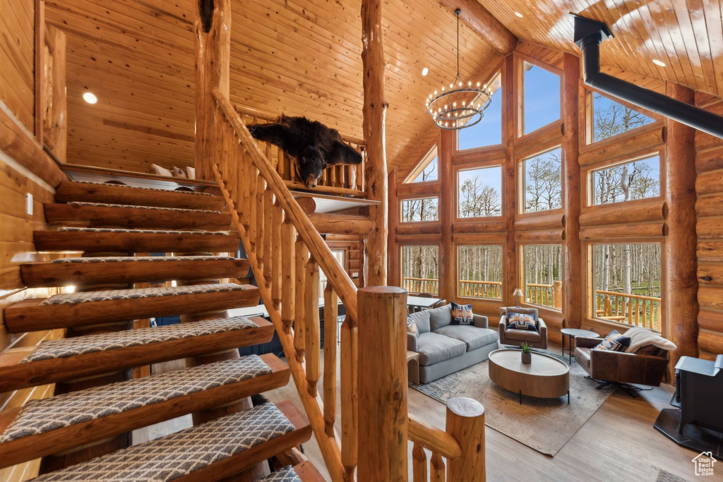 Living area with high vaulted ceiling, wood ceiling with exposed beams, rustic walls, wood finished floors, and stairway