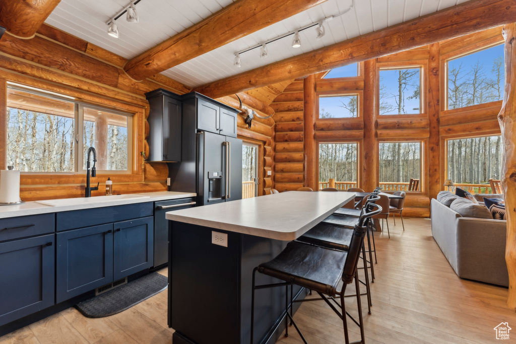 Kitchen with rail lighting, a sink, dishwashing machine, high end refrigerator, and log walls
