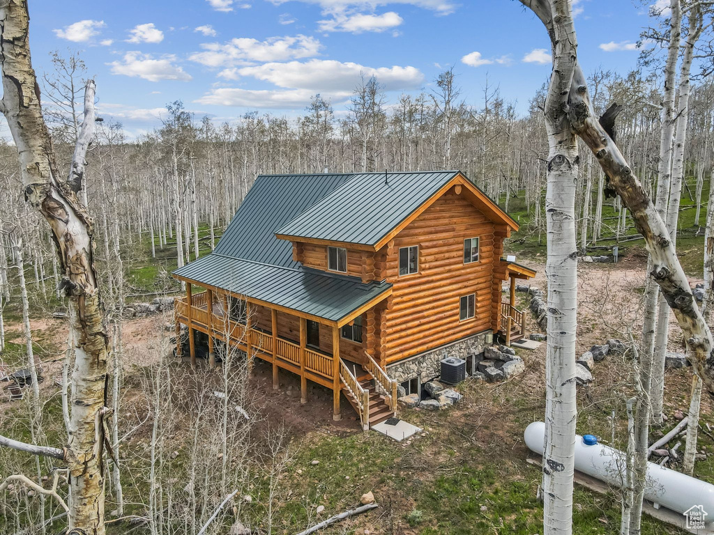 Back of property featuring log siding, stairway, metal roof, cooling unit, and a standing seam roof