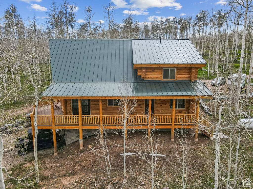 View of front of property featuring log siding, a porch, and metal roof
