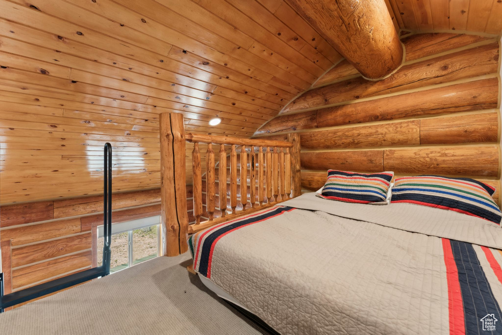 Unfurnished bedroom featuring log walls, lofted ceiling, and wooden ceiling