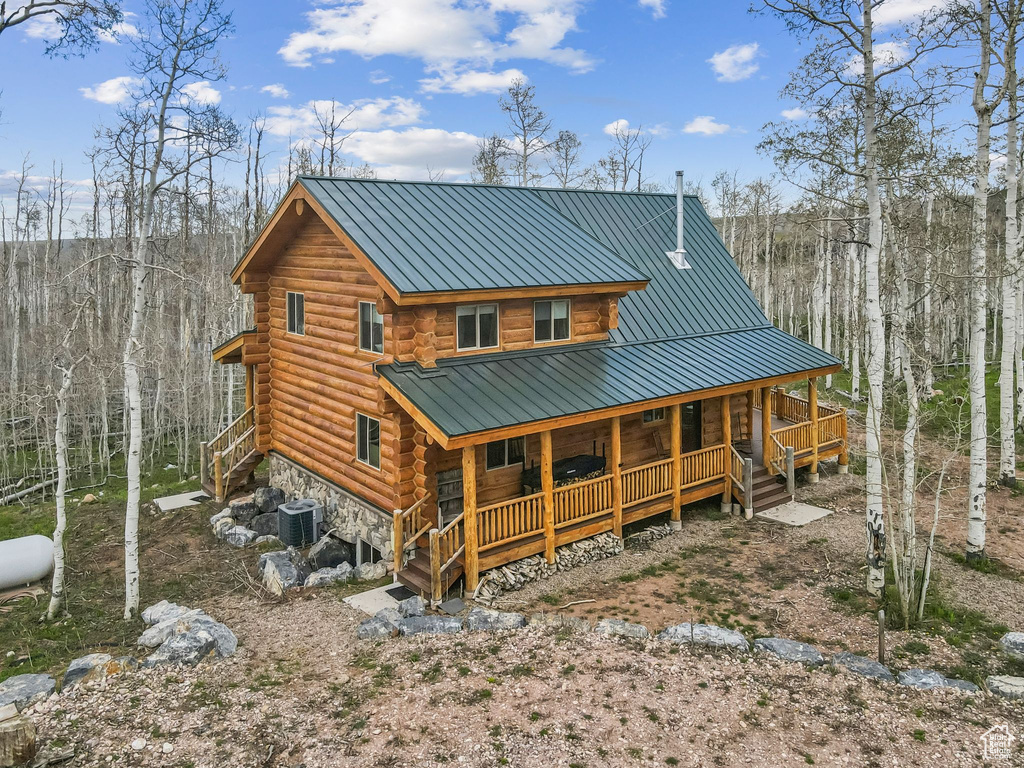 Rear view of property featuring a porch, log siding, a standing seam roof, metal roof, and central AC unit