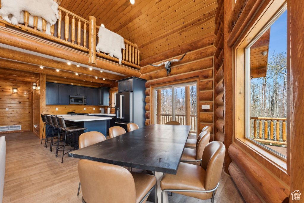 Dining space with log walls, wood ceiling, and light wood-style flooring