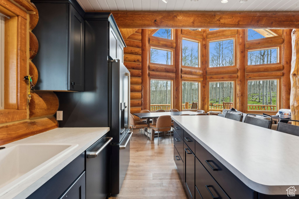Kitchen with rustic walls, stainless steel dishwasher, light wood-type flooring, a sink, and high quality fridge
