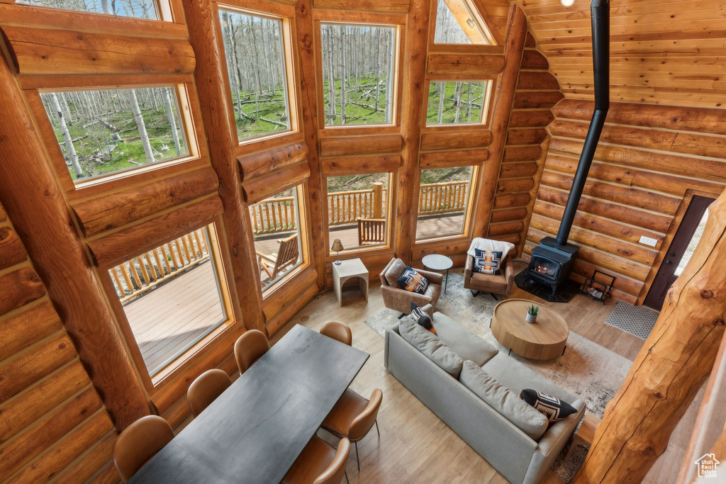 Living room with a wood stove, wood finished floors, log walls, and wood ceiling